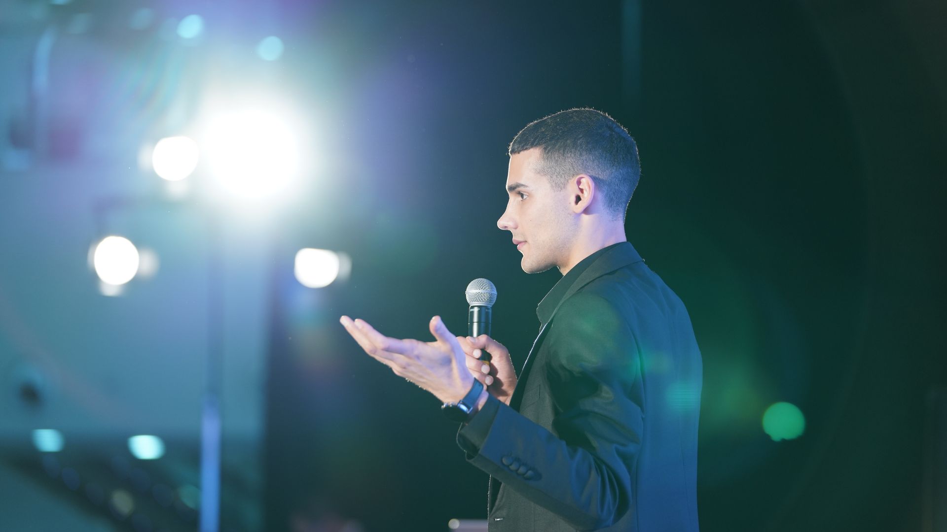 A speaker mid-address, lit by stage lighting