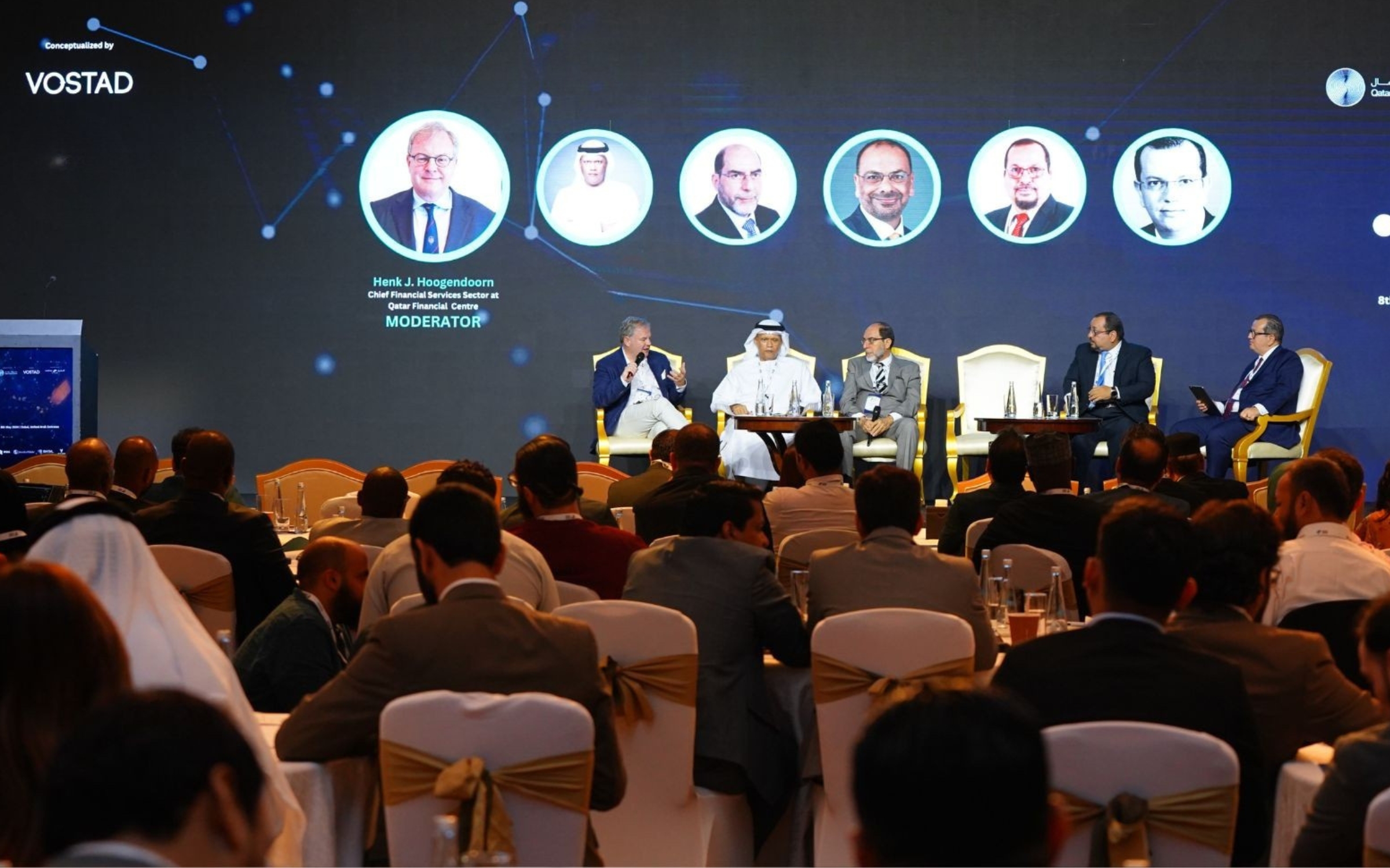 A panel session under way on stage at a Vostad forum, with delegates seated in the room.