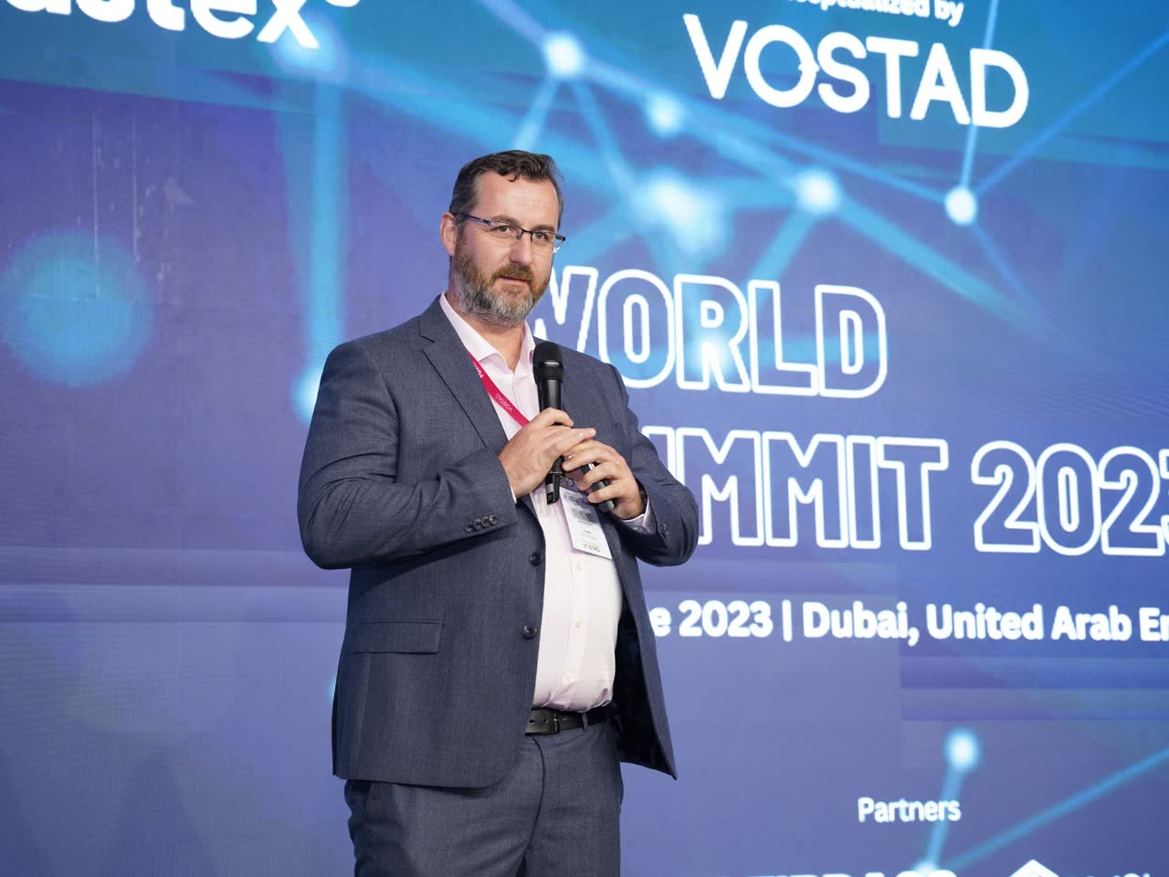 A speaker addressing a summit audience from the stage